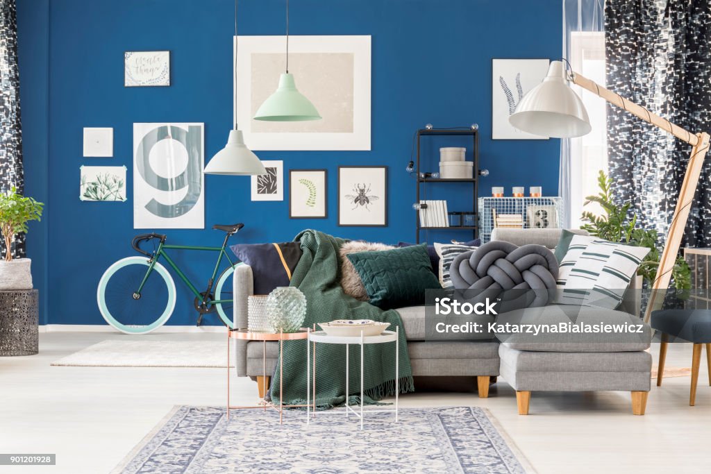 Living room with oversize lamp Living room interior with oversize lamp standing over a gray corner sofa with green blanket Domestic Room Stock Photo