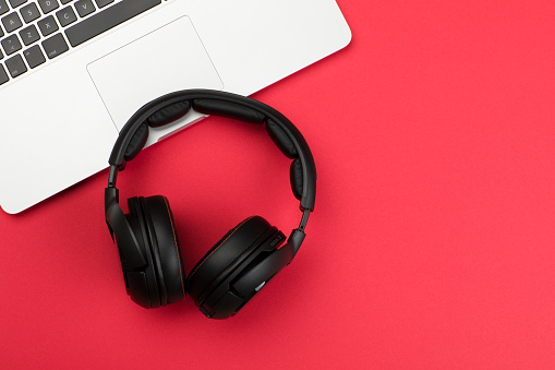 Headphones and laptop on red background
