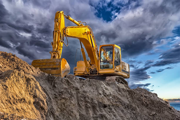A stopping yellow excavator A stopping yellow excavator at an incredibly beautiful sunset earthwork stock pictures, royalty-free photos & images