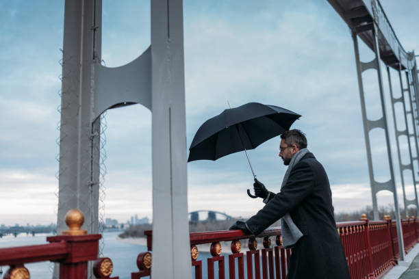 istock handsome lonely man with umbrella standing on bridge 901203130