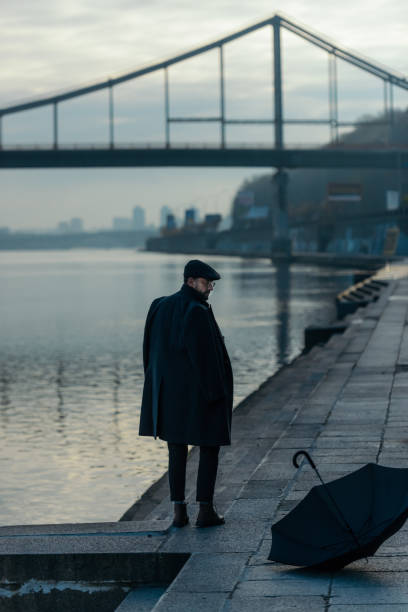 istock handsome middle aged man looking at umbrella lying on river shore 901205112