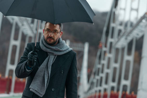 istock handsome middle aged man with umbrella walking by bridge 901206594
