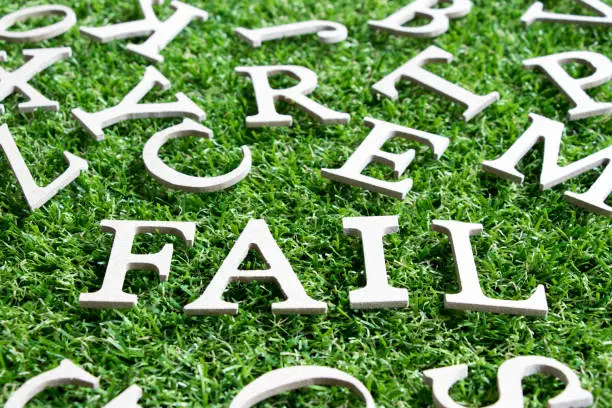 Photo of Wood alphabet in wording fail  on artificial green grass background