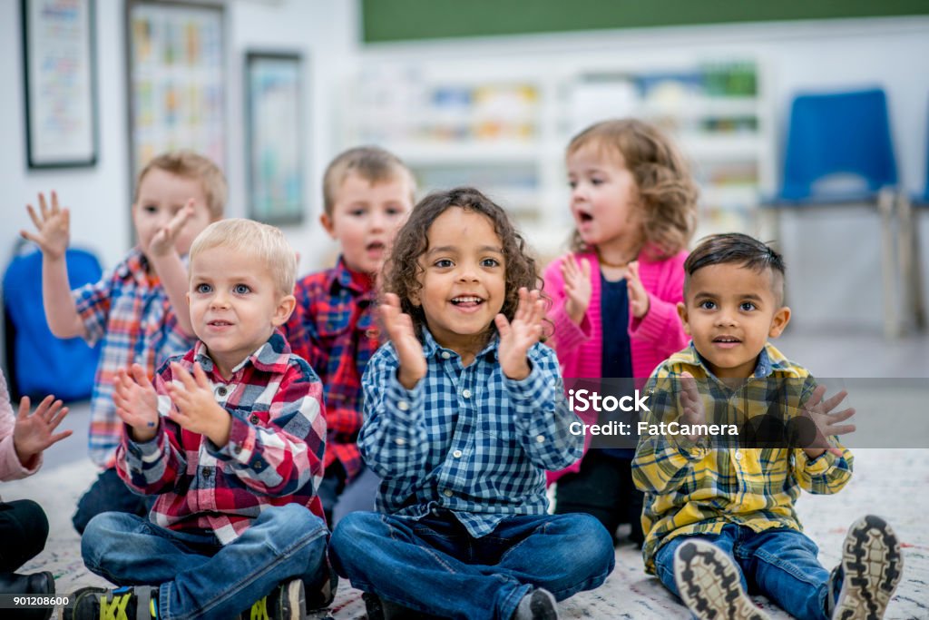 Learning Rhythm A multi-ethnic group of young children are at a preschool. They are sitting on the carpet and clapping along to a music CD. Child Stock Photo