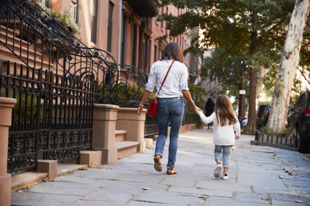 istock Mother and daughter walking down the street, back view 901211852