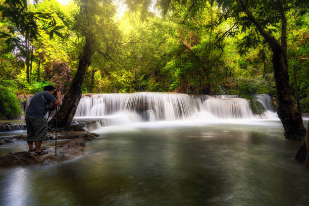 fotograf biorąc scenę zdjęć piękny wodospad w głębokim lesie, wodospad pha tat, prowincja kanchanaburi, tajlandia, koncepcja podróży natura - natural phenomenon waterfall rock tranquil scene zdjęcia i obrazy z banku zdjęć