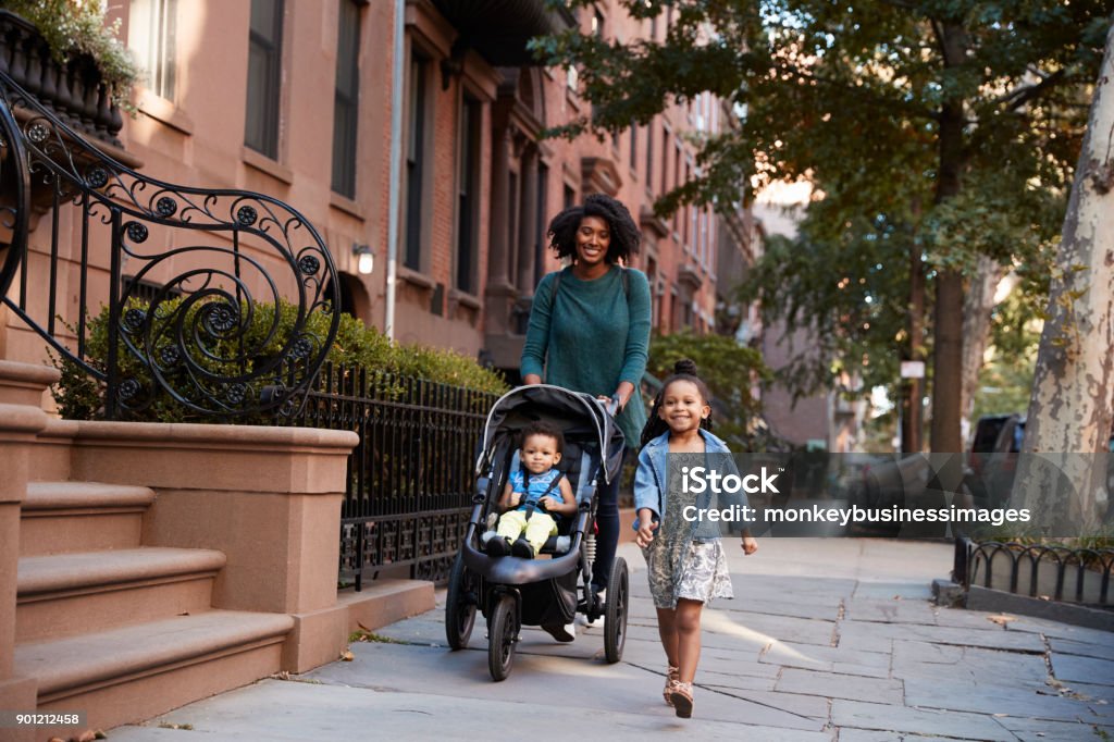 Madre y dos hijas de caminar por la calle - Foto de stock de Cochecito para niños libre de derechos