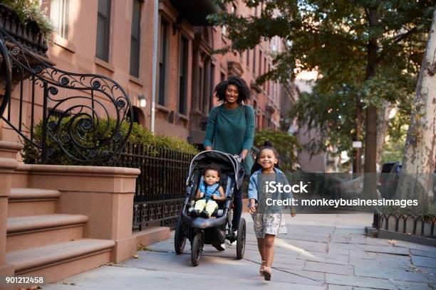 Mother And Two Daughters Taking A Walk Down The Street Stock Photo - Download Image Now