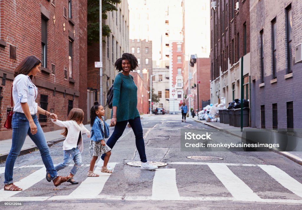 Two mother friends with two daughters crossing the road City Stock Photo