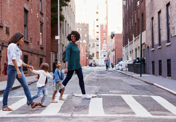 Photo of Two mother friends with two daughters crossing the road