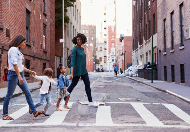 two mother friends with two daughters crossing the road - cruzar imagens e fotografias de stock