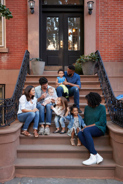 Two families with kids sitting on front stoops, vertical