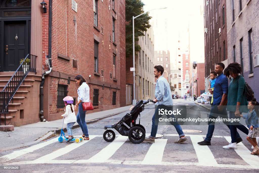 Due famiglie con figlie che attraversano la strada - Foto stock royalty-free di Famiglia