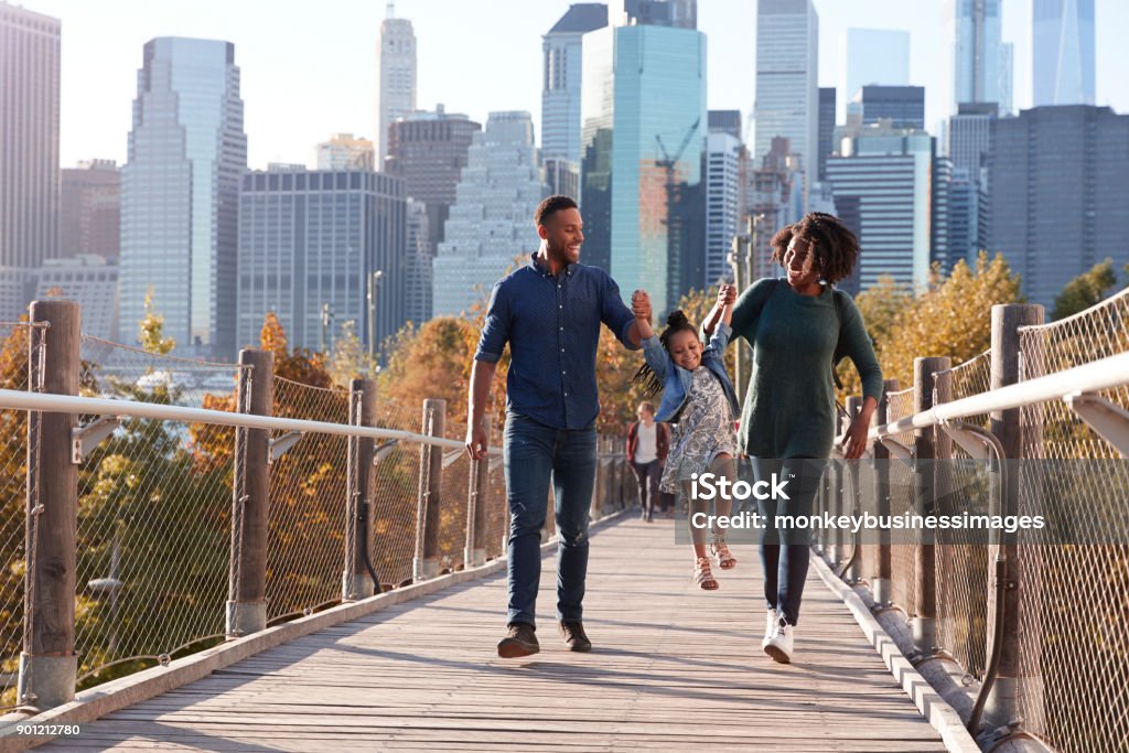 Young family with daughter taking a walk on footbridge Family Stock Photo