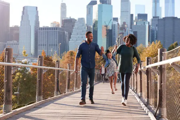 Photo of Young family with daughter taking a walk on footbridge