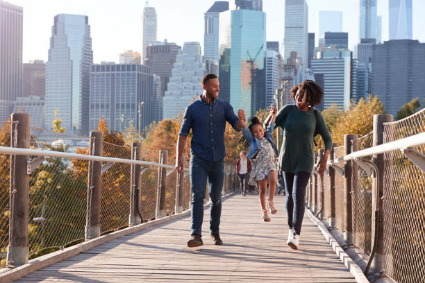 young family with daughter taking a walk on footbridge - urban bridge imagens e fotografias de stock