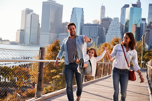 Young family with daughter taking a walk on footbridge