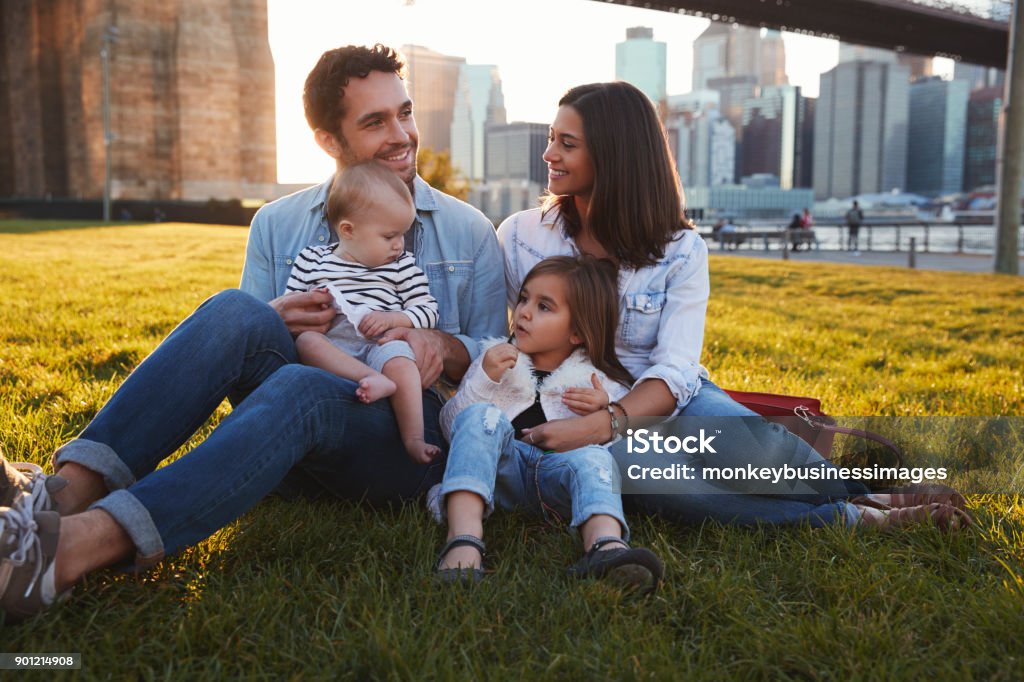 Young family with two daughters sitting on lawn, close up Family Stock Photo