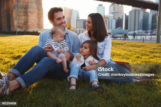 Young Family With Two Daughters Sitting On Lawn Close Up Stock Photo - Download Image Now