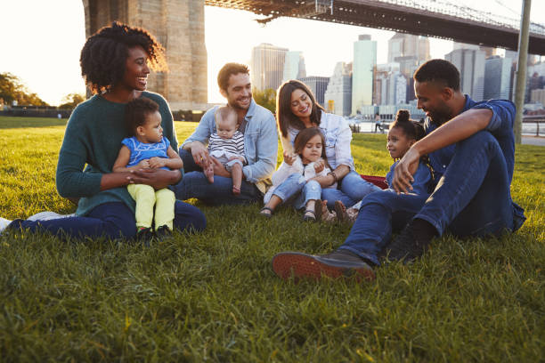 istock Two families with daughters sitting on lawn 901214910