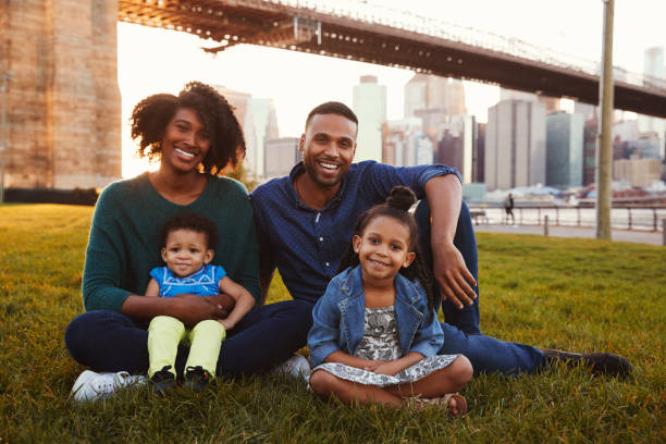 istock Young family with two daughters sitting on lawn, close up 901214932