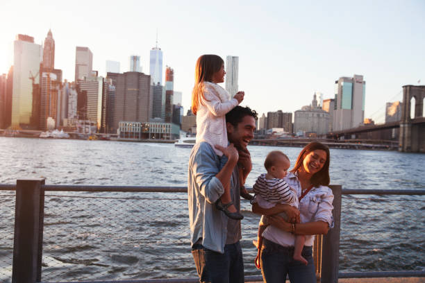 família de jovem com filhas de pé no cais, vista lateral - adult couple four people urban scene - fotografias e filmes do acervo