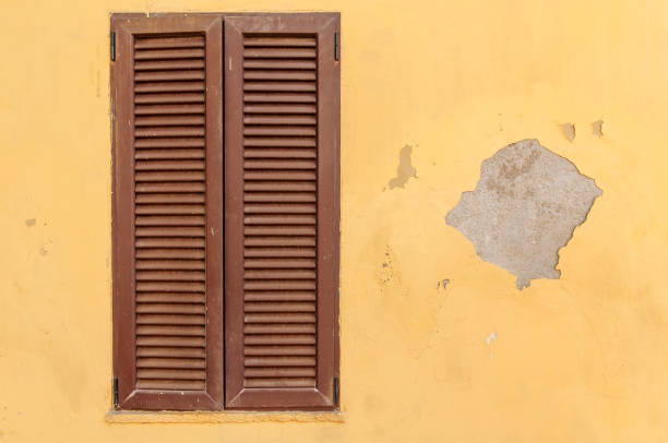 istock Brown wooden texture window frame on a yellow old cement house 901219814