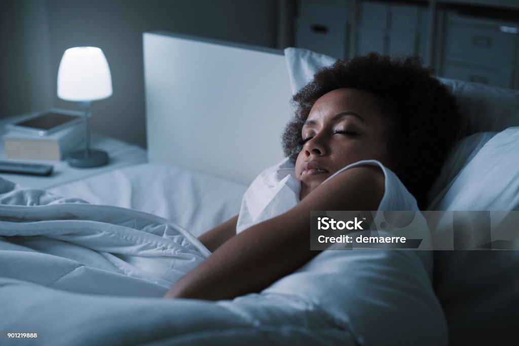 Woman sleeping in her bed Young african woman sleeping in her bed at night, she is resting with eyes closed Sleeping Stock Photo