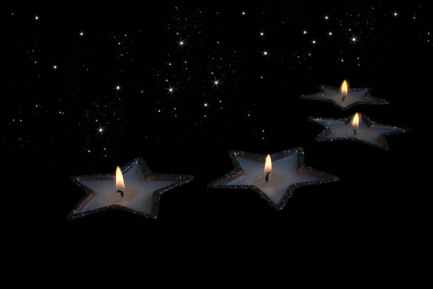 Two candles in the shape of stars and their reflection in the mirror. On the black background is the starry sky.