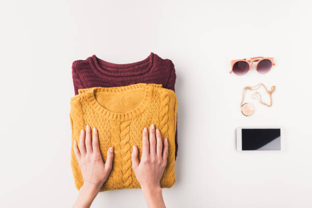hands with sweaters, accessories and smartphone