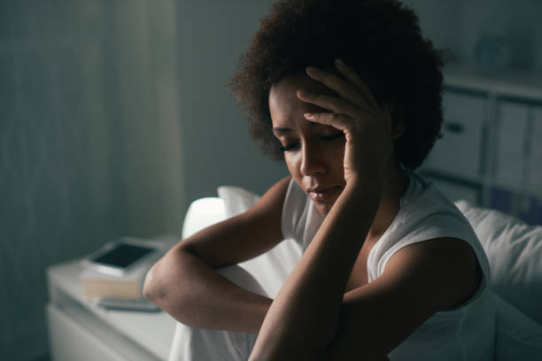 Sad woman suffering from insomnia Sad depressed woman suffering from insomnia, she is sitting in bed and touching her forehead, sleep disorder and stress concept trouble sleeping stock pictures, royalty-free photos & images