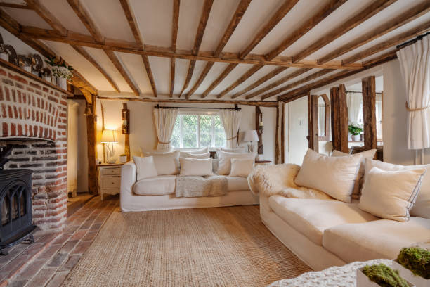 Cottage living room with original features 16th Century English cottage living room with cast iron fire beutifully decorated in pastel colours and furnishings with expose brick floor, expose brick chimney breast, beams and timbers, matching chairs and cushions. cottage stock pictures, royalty-free photos & images