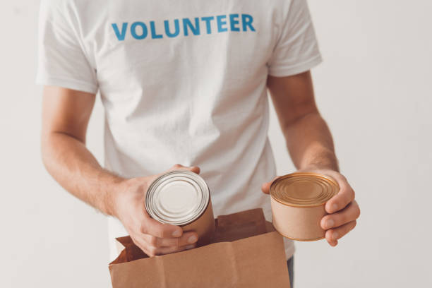 istock volunteer putting tin cans in paper bag 901235692