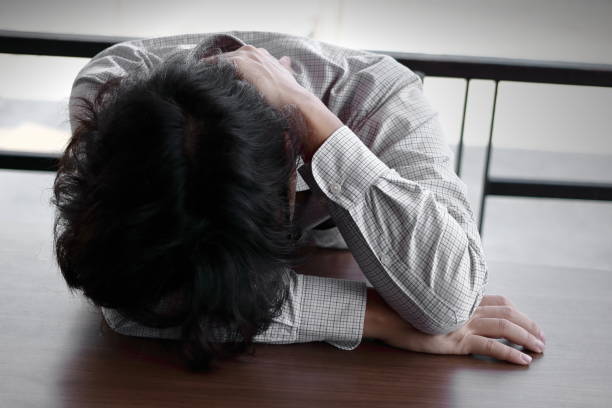istock Tired overworked young Asian business man lying with face down on office desk 901235966