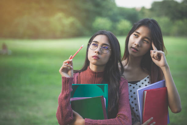 istock two girls thinking in park and hold the books, create knowledge concept 901243842