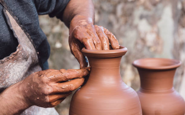 Man molding a clay pot Close up view of an adult male using their own hands to make a ceramic vase. pottery photos stock pictures, royalty-free photos & images