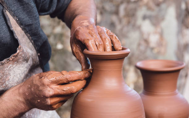 Man molding a clay pot Close up view of an adult male using their own hands to make a ceramic vase. craft product stock pictures, royalty-free photos & images