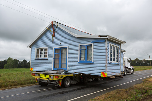 Wooden house on back of truck, being moved to new location in New Zealand