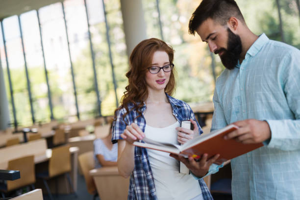 istock Happy young university students studying with books in library 901257582