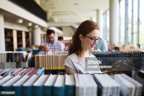 Portrait Of A Pretty Smiling Girl Reading Book In Library Stock Photo - Download Image Now