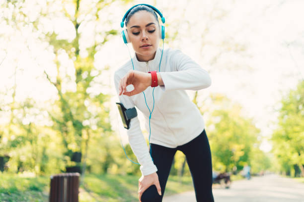 Sportswoman checking pulse Young woman sports training in the park and checking pulse on smartwatch pedometer photos stock pictures, royalty-free photos & images