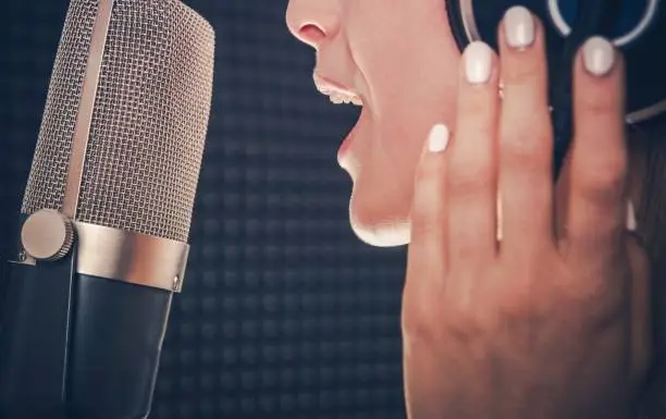 Song Recording by Singer. Professional Audio Recording in a Studio. Caucasian Female Singer with Headphones Closeup Photo. Music Industry Theme.