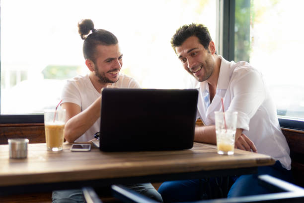 istock Two Happy Man Sitting In Coffee Shop While Using Laptop Computer 901285386