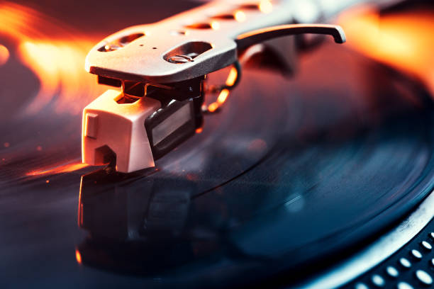 Turntable Needle on Vinyl Closeup A close up shot of a running record player spinning out some music, dramatically lit with orange light.  Horizontal with copy space. deck stock pictures, royalty-free photos & images