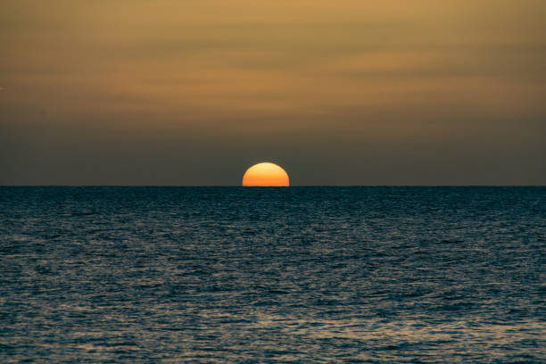 istock Golden sunset over a calm still ocean sea 901289136