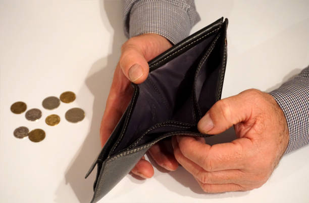 istock Black empty wallet in man's hand with some coins in the background 901303562