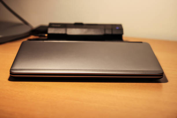 istock Sleek stylish silver ultra notebook on desk. Computer docked in docking station. 901307866