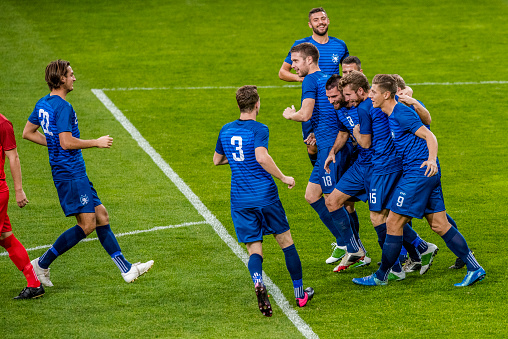 Soccer team in blue jerseys on the field celebrating a goal.