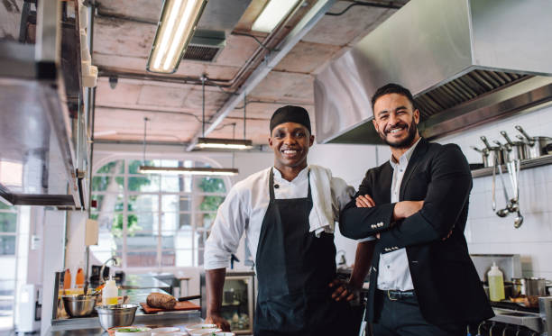 restaurant owner with chef in kitchen - commercial kitchen restaurant chef food service occupation imagens e fotografias de stock