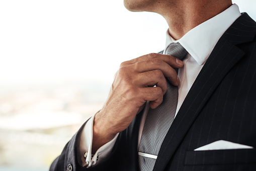 Close up of man in business suit correcting tie. Cropped shot of businessman adjusting his look.